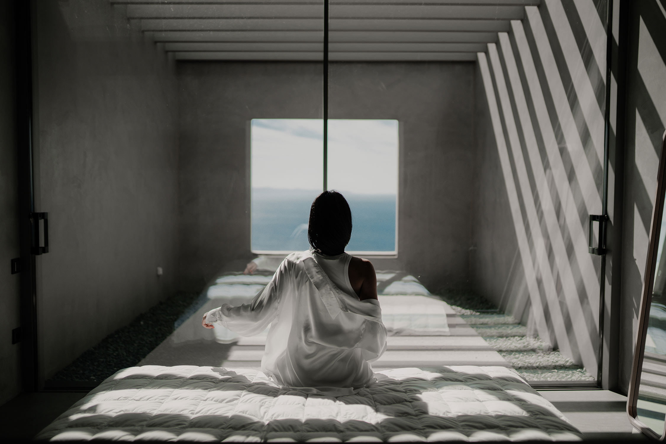 Guest sitting at a framed sea window in a concrete room