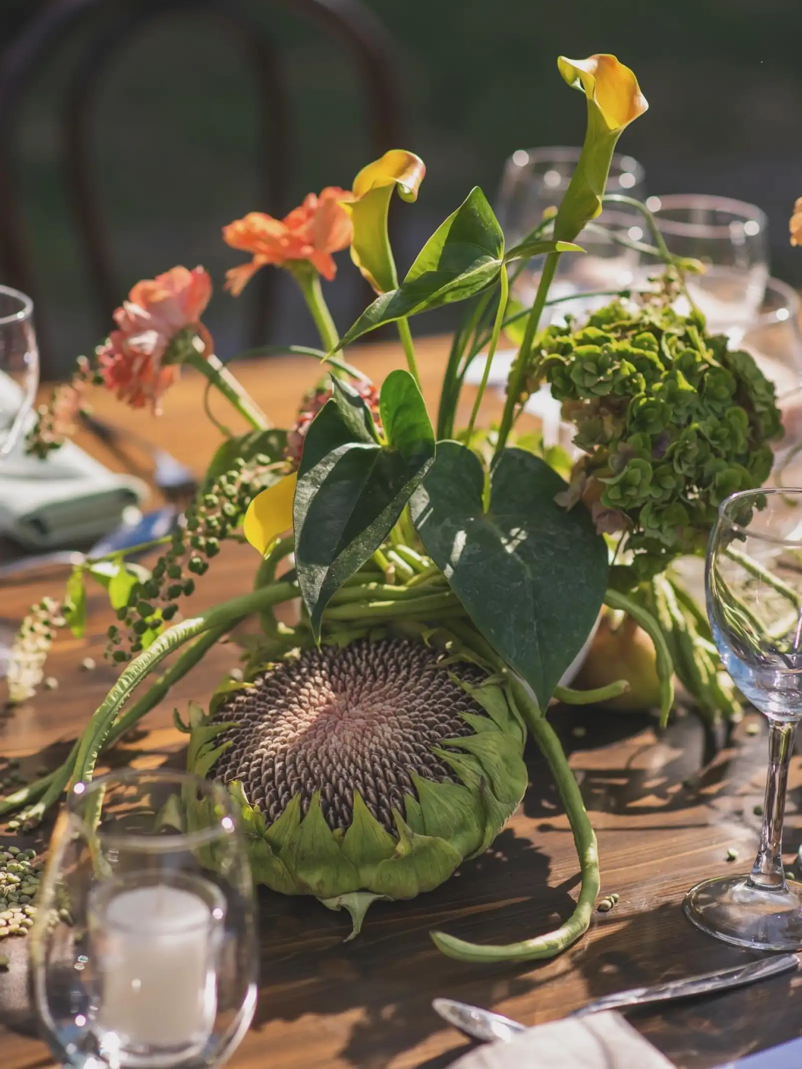 Centro de mesa con girasol y calas amarillas en composición moderna para evento diurno con estética botánica.