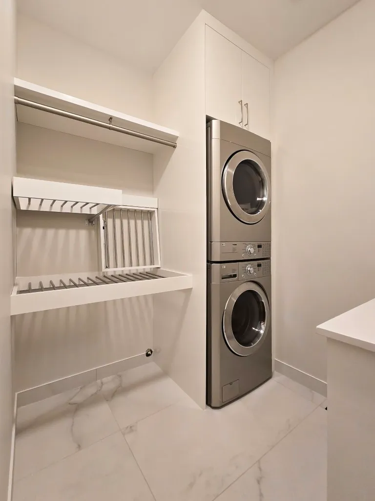 Image of Laundry room design by KHD Homes featuring stacked washer dryer and custom cabinetry layout design.