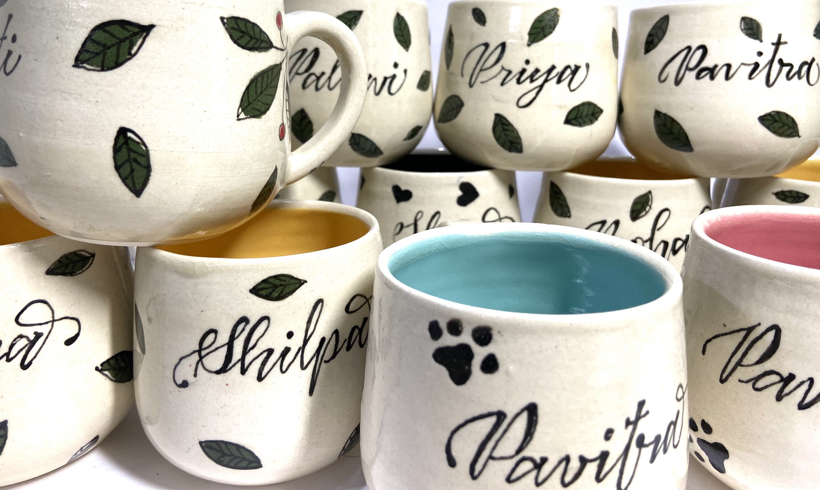 A captivating assortment of handmade ceramic mugs with unique underglaze designs. Each mug features a custom name, adding a personal touch to your daily sips of joy.