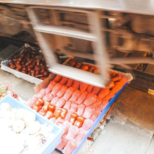 기차가 머리 위로 이동하며 바닥에 놓인 트레이 속 비닐로 포장된 물품들.