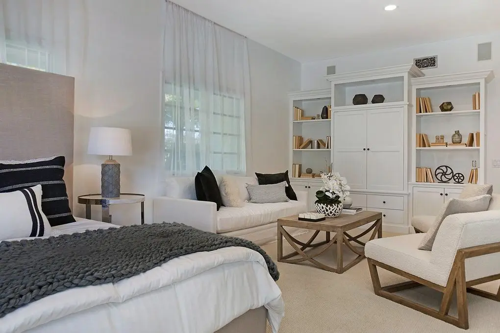 'Port Streets Remodel' tranquil bedroom with a knit throw, white cabinetry, and open shelving with decorative items.