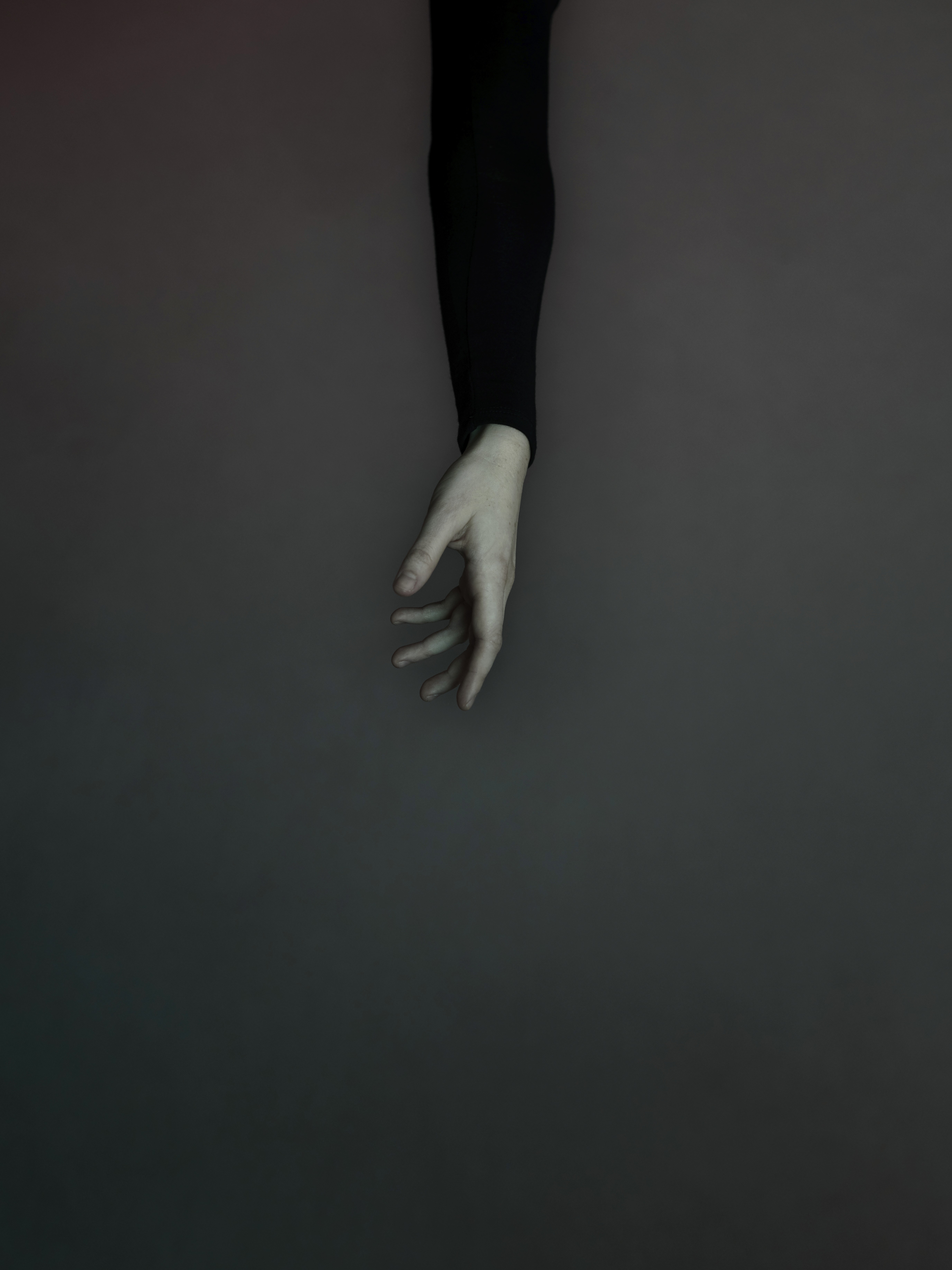 An elegant and classical hand reaches down into the frame bathed in moody tones.