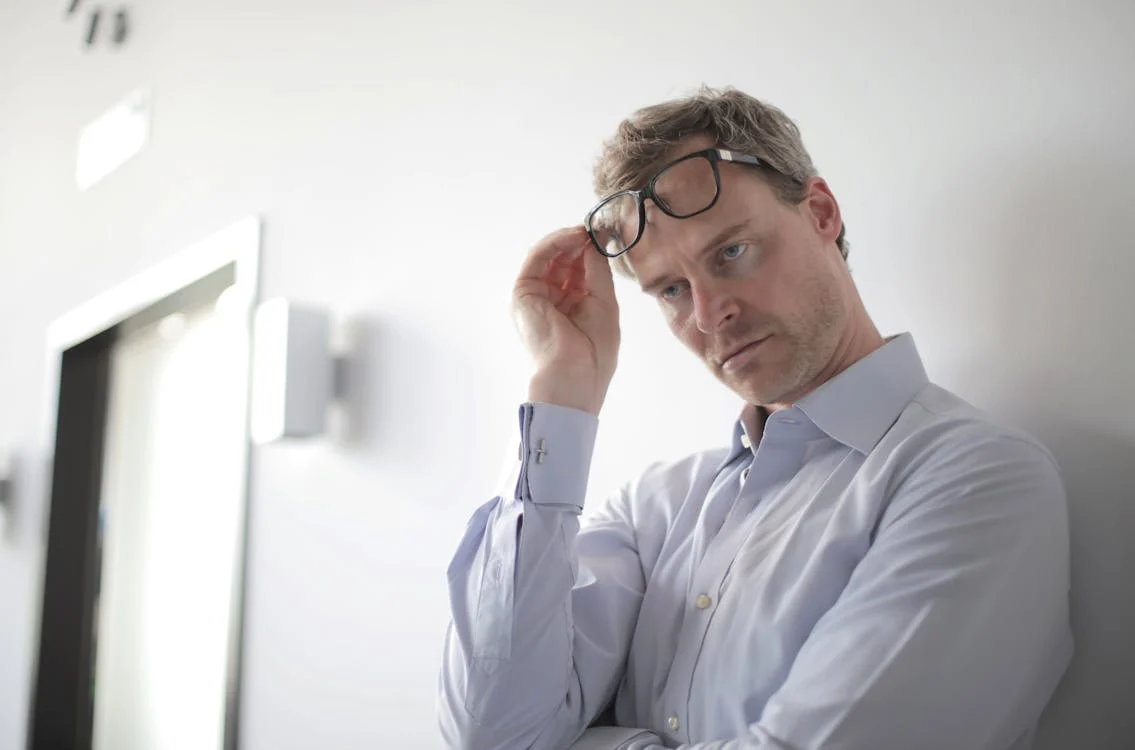 man leaning on wall, lifting glasses