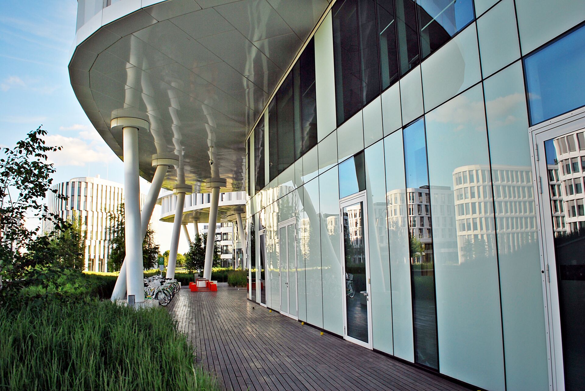 Modern office interior with glass walls, wooden accents, and a person walking up a staircase in motion blur.