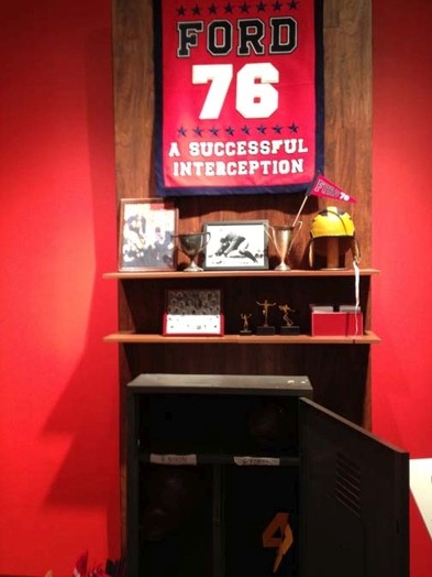 A shelf with cups and triangle flags and a Ford 76 Poster
