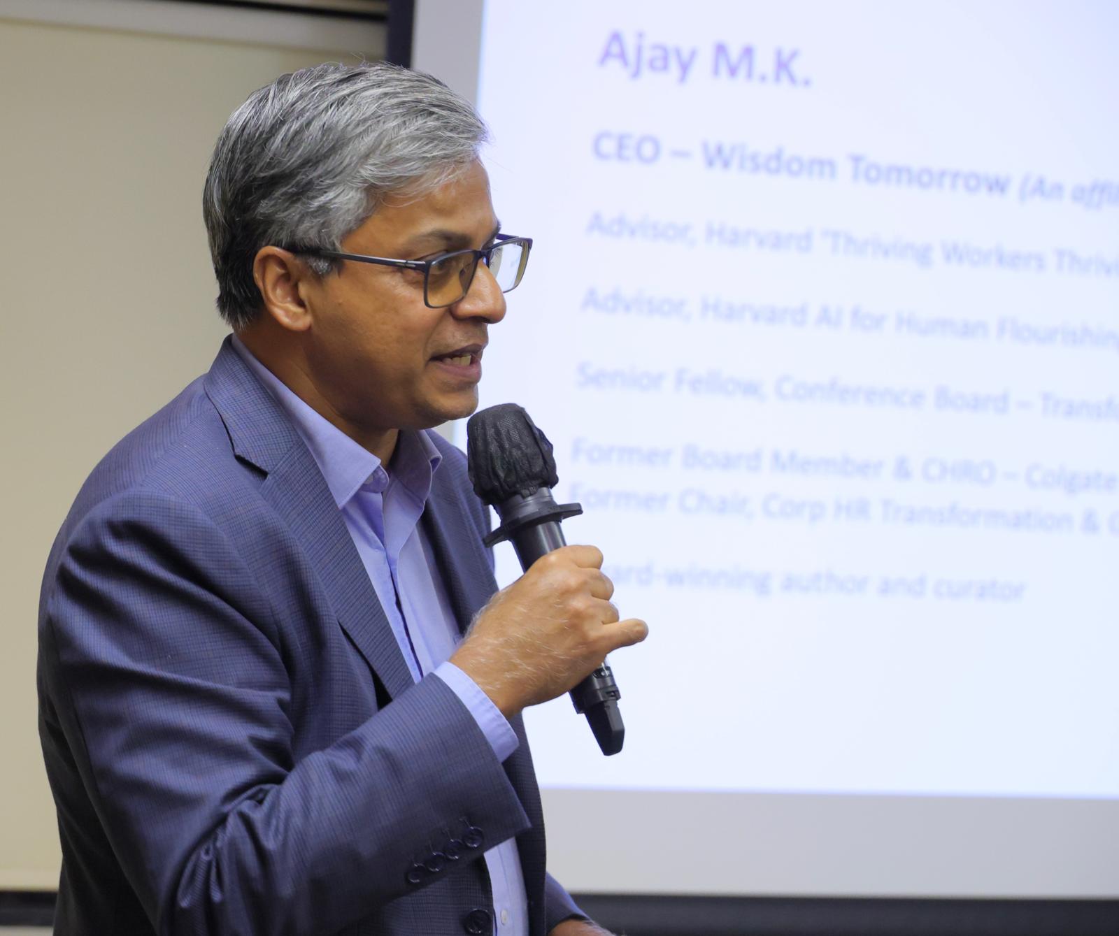 Smiling woman in beige linen outfit standing indoors with plants and books in the background.