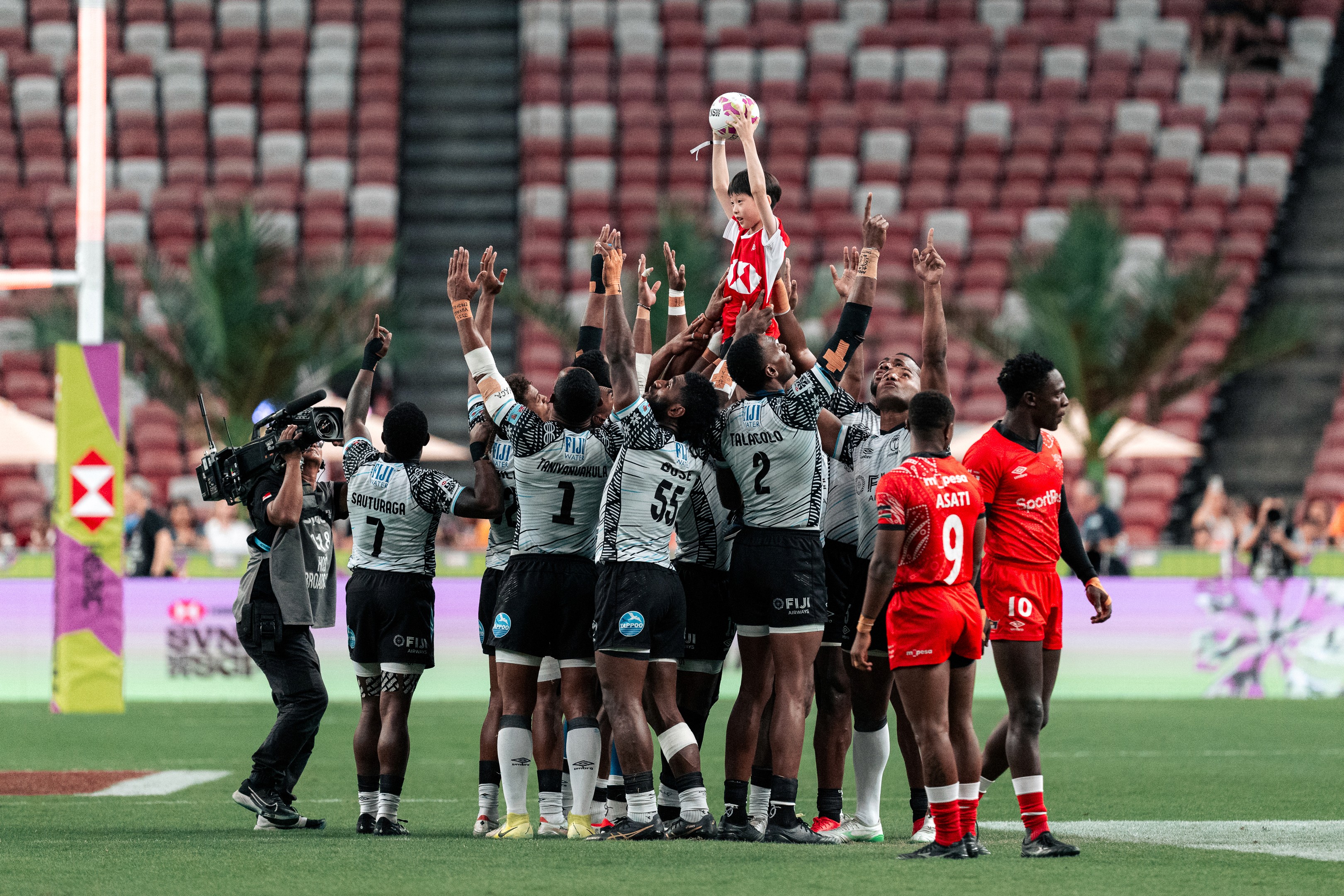 Fiji players lift a HSBC ball boy as part of a pre-match ritual before the HSBC SVNS Singapore 2025