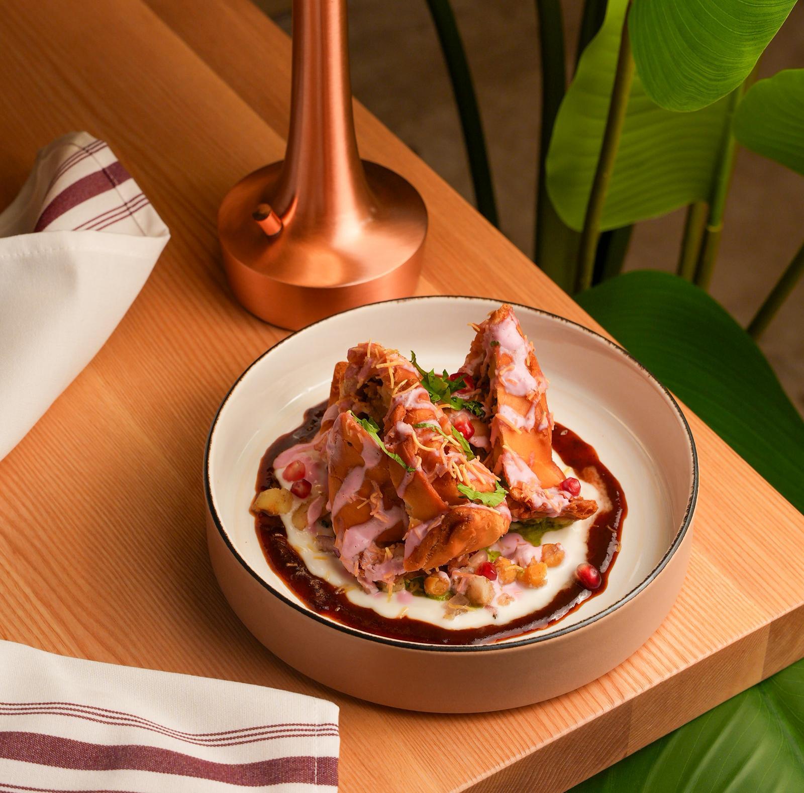 Pink samosa chaat topped with yogurt, chutneys and pomegranate at Dhoom Greektown Toronto