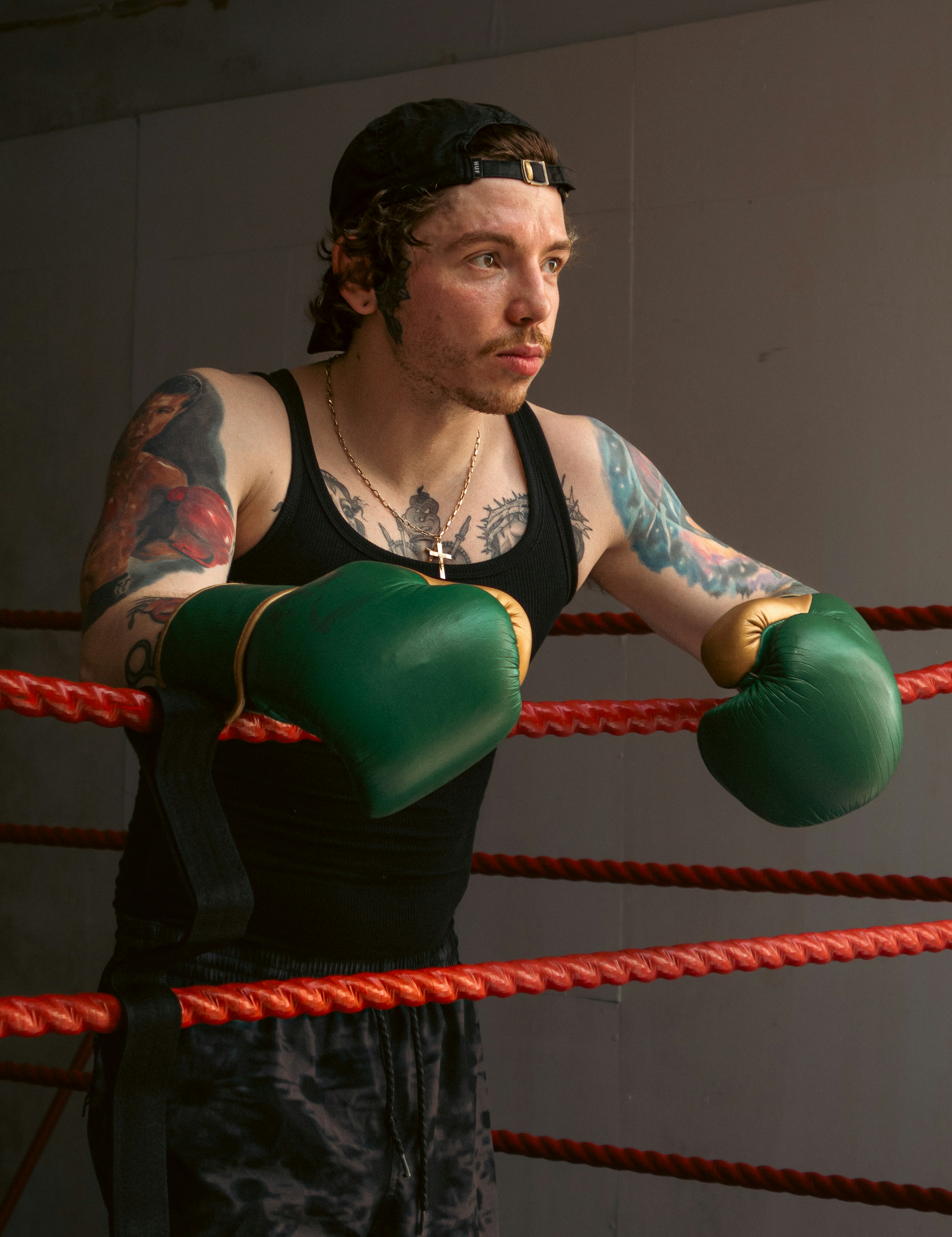 Image of a man leaning on the ropes of a boxing ring.