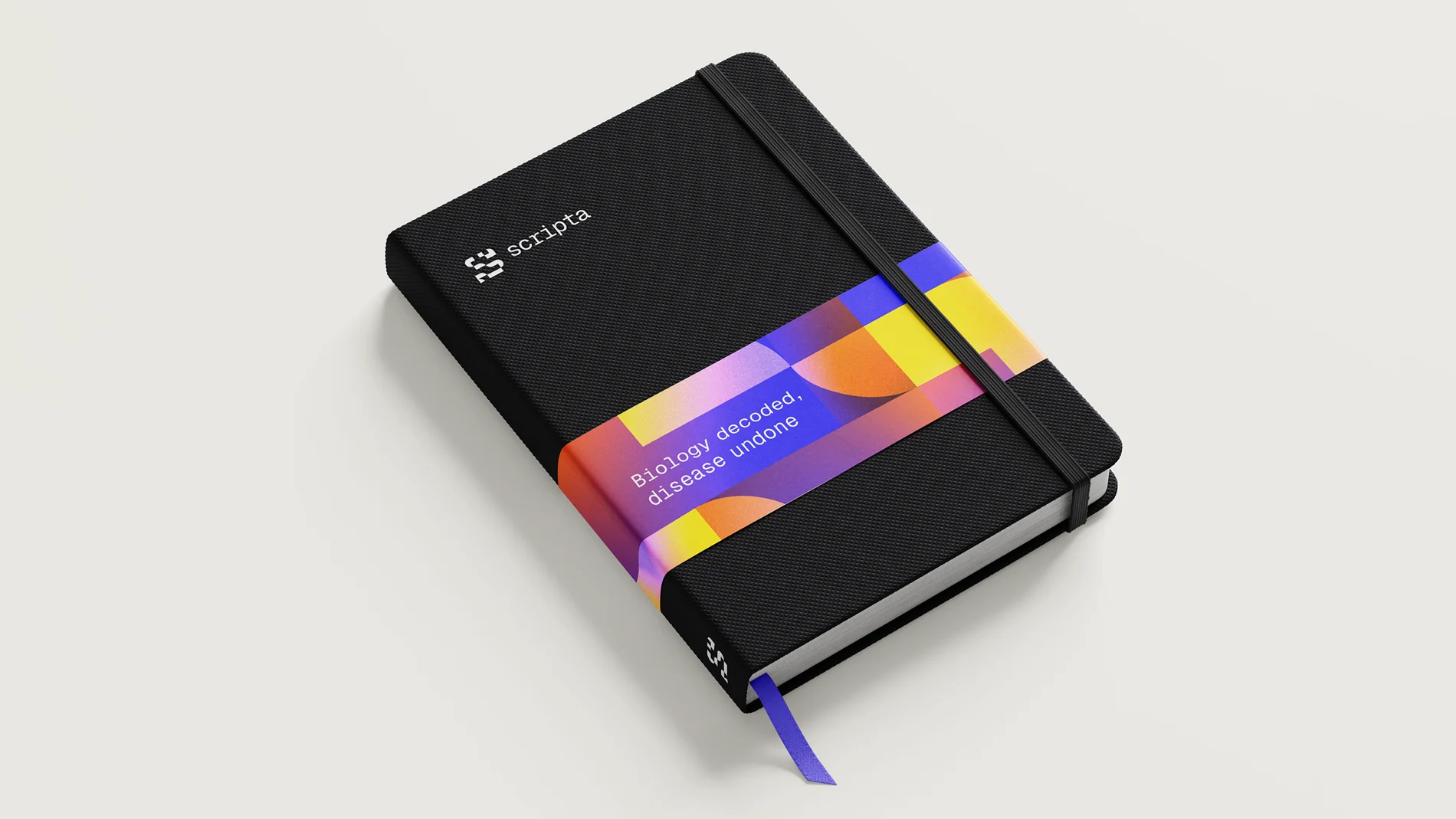 Black notebook with Scripta branding and a colourful geometric band wrapped around it, featuring the tagline ‘Biology decoded, disease undone’