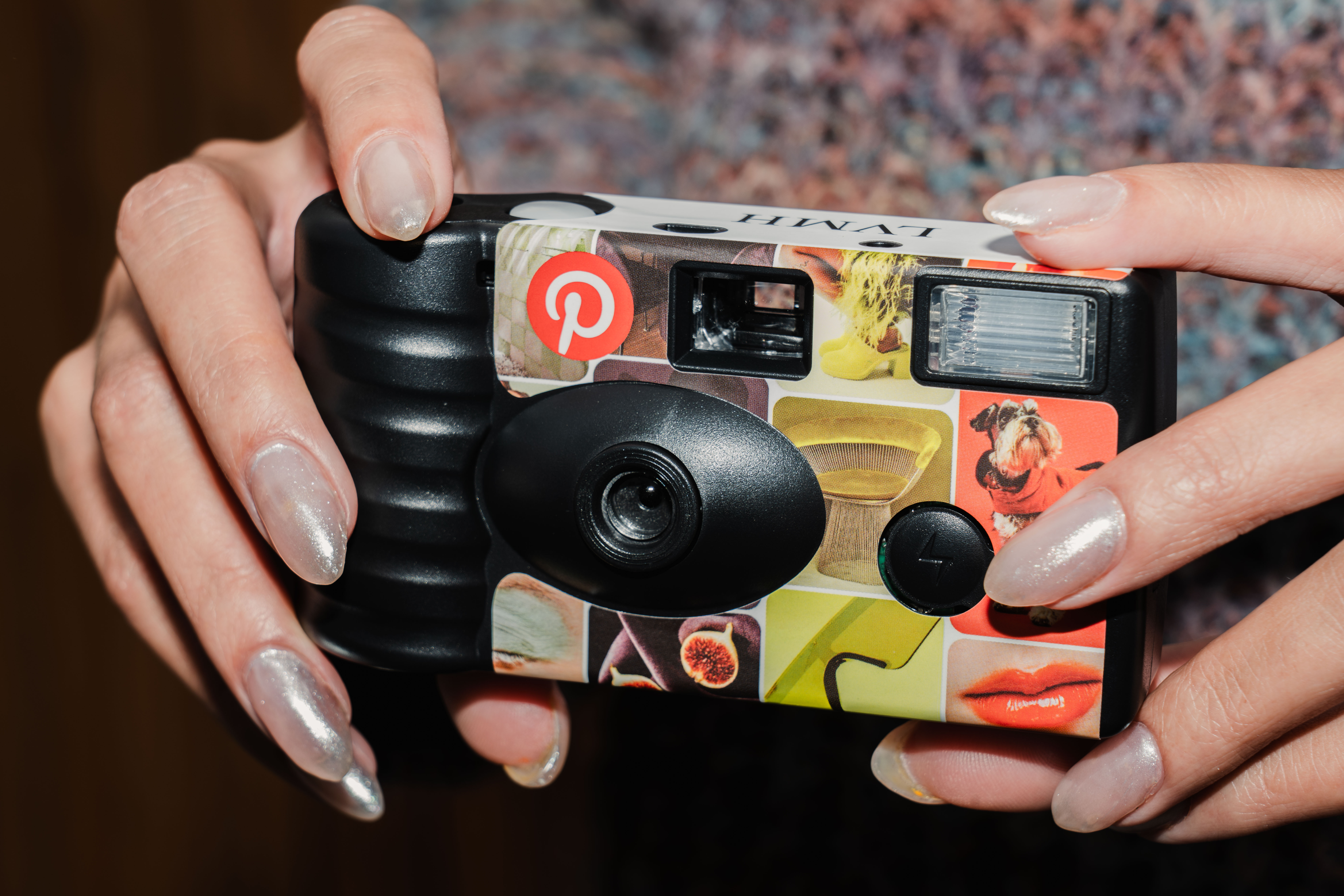 a close up shot of someone with pearlescent long nails holding a disposable camera branded with pinterest imagery