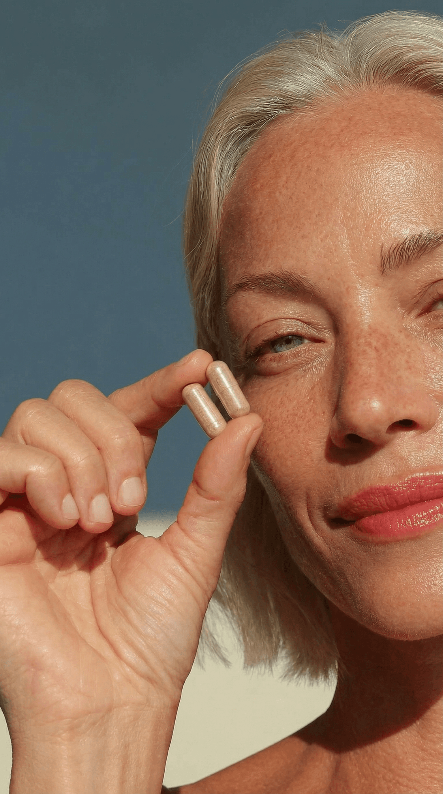 A close-up of a hand wearing multiple decorative rings against a blue background.