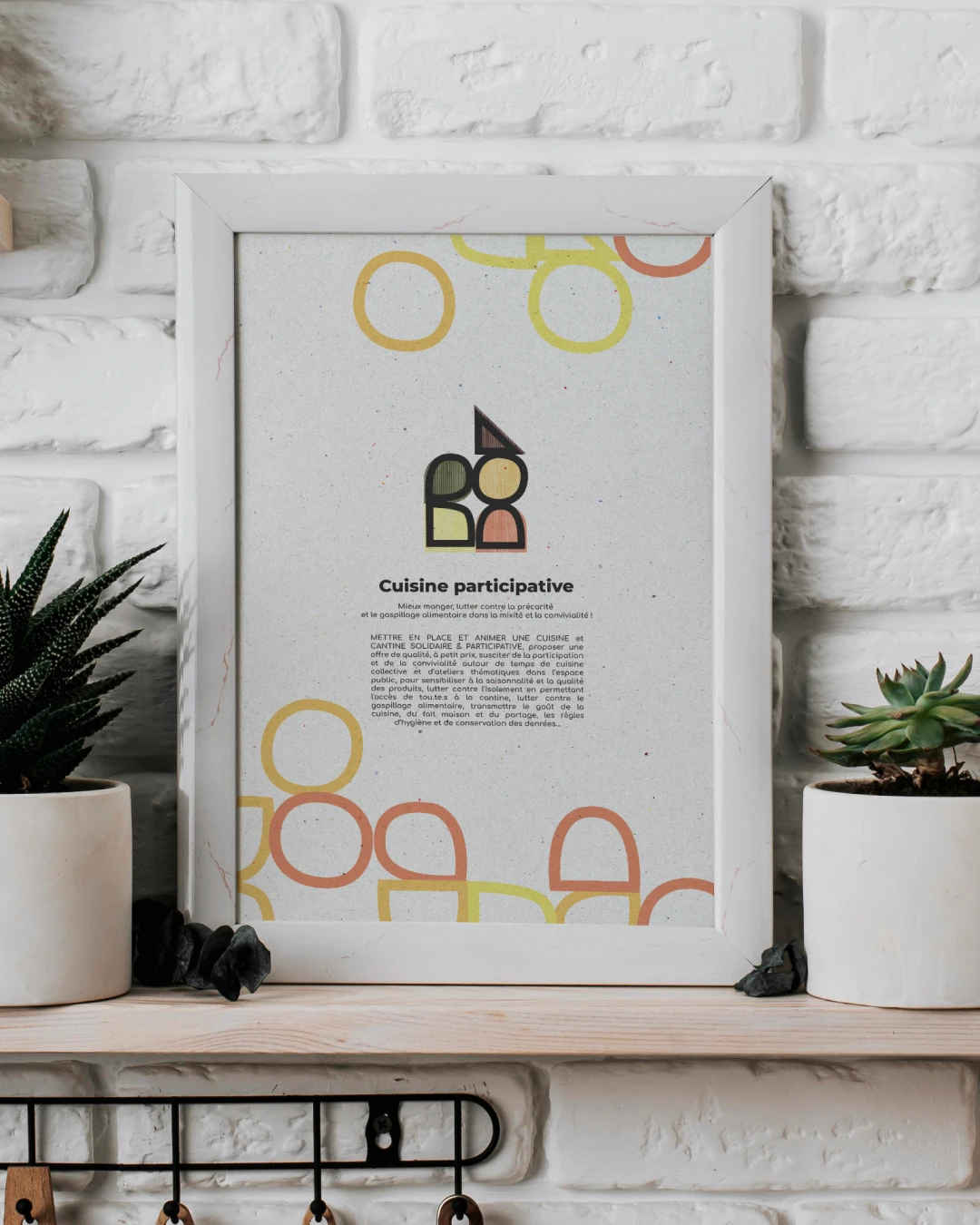 Mockup affiche Cuisine participative Toi(t) Pour Tous·tes encadrée in situ — logo, motif Bauhaus et texte descriptif sur fond papier recyclé, déclinaison print lieu social Toulouse, Tartelette Concept
