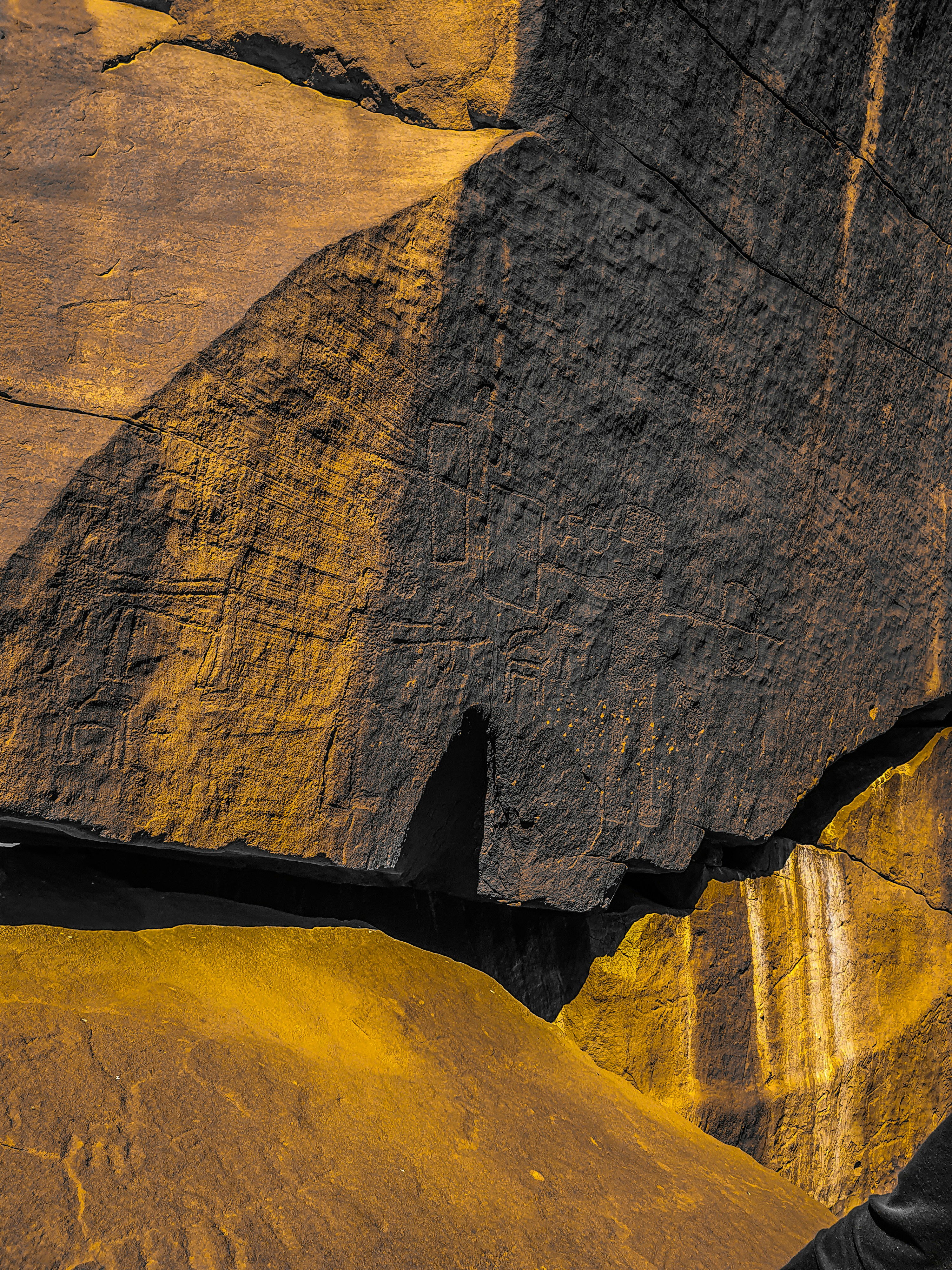 Rock face consisting of dark and yellow mineral deposits, creating a streaked surface pattern.