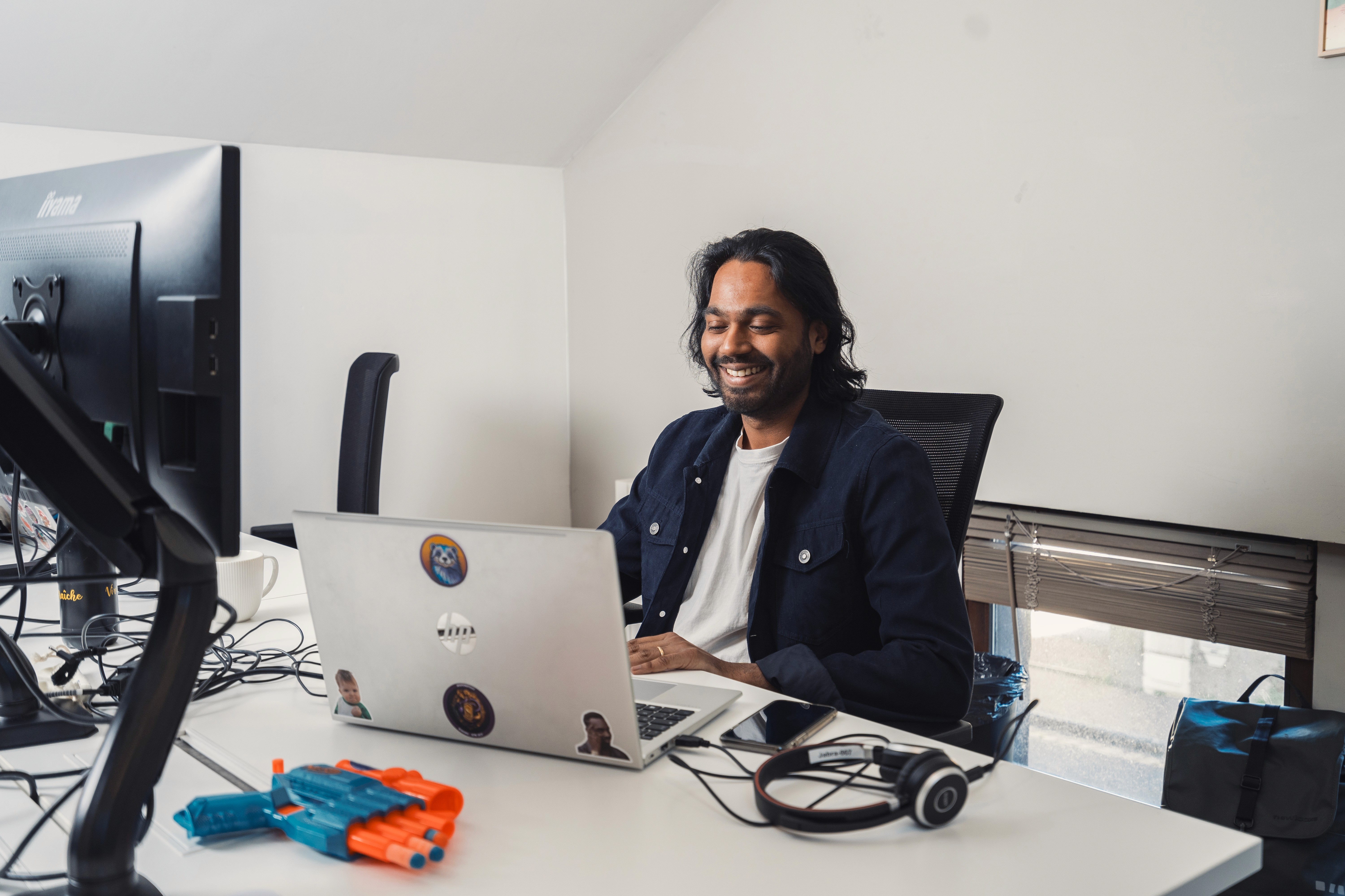 homme installé sur un bureau qui sourit en regardant son ordinateur