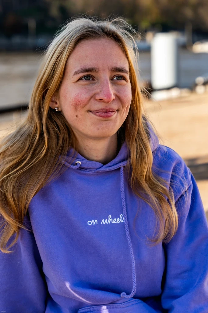 Camille ZWICK, cofondatrice de On Wheels, portant un hoodie violet et souriant en extérieur