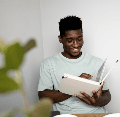 A man smiling as he reads a book