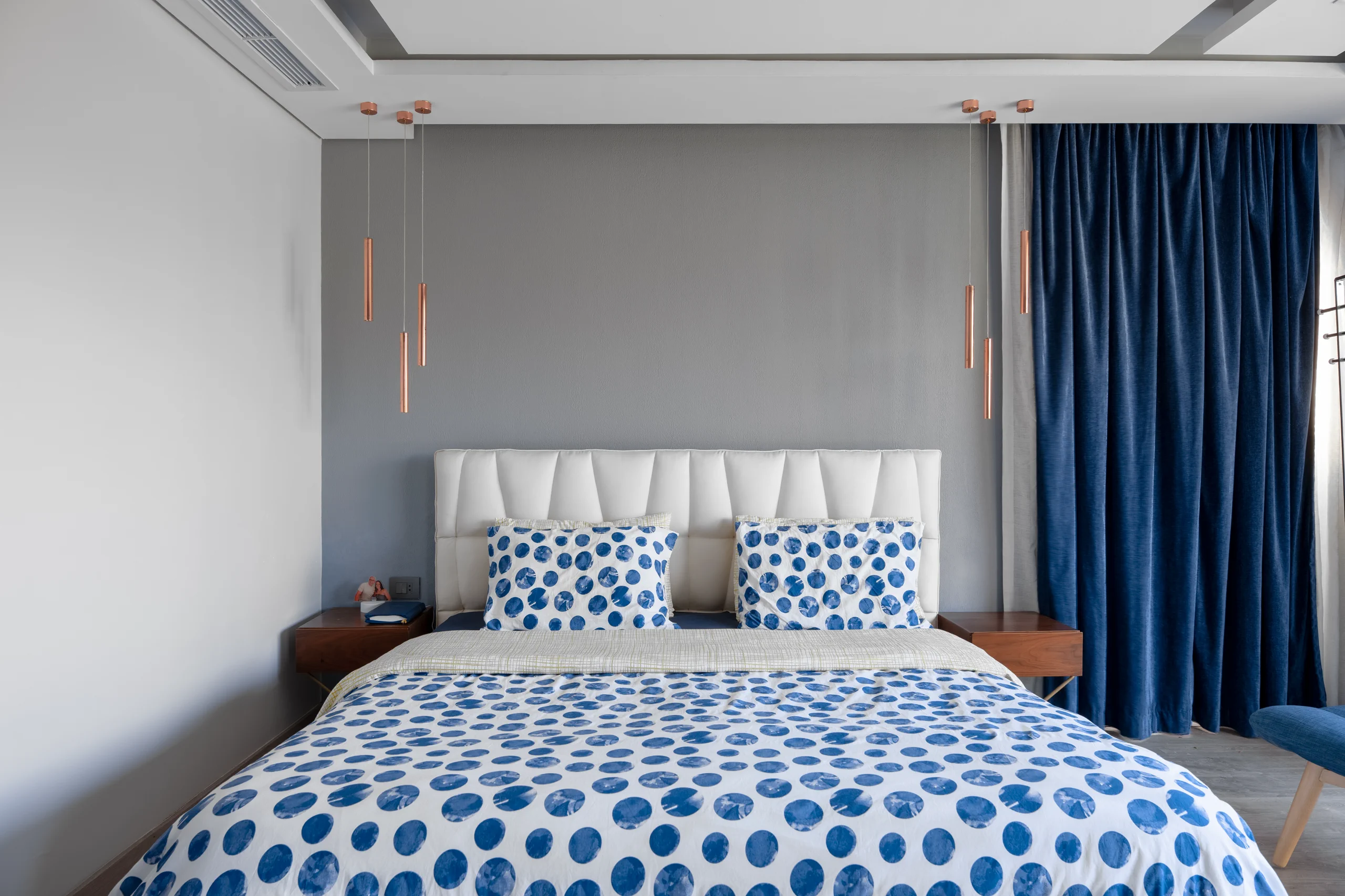 Master bedroom at Caesar SODIC Villa with blue patterned bedding and deep blue curtains.