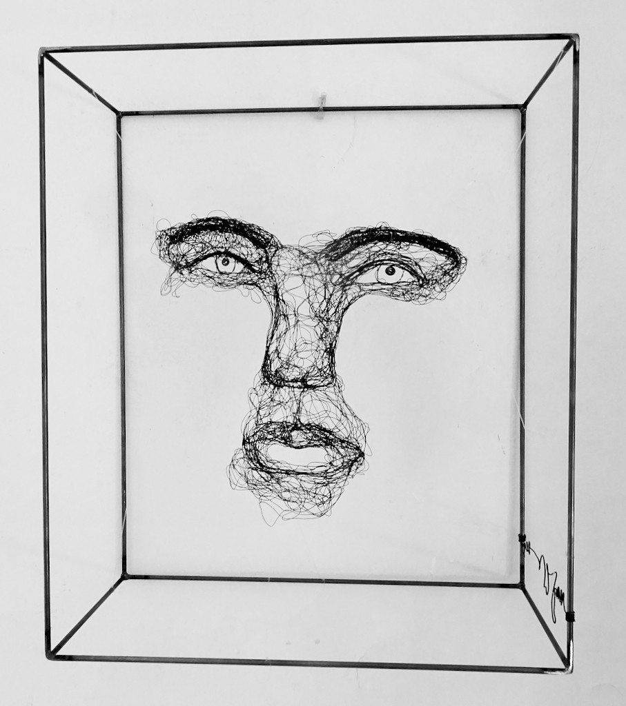 Sculpture en fil de fer représentant le visage d'une femme dans un cadre en fil de fer, vue détaillée de face