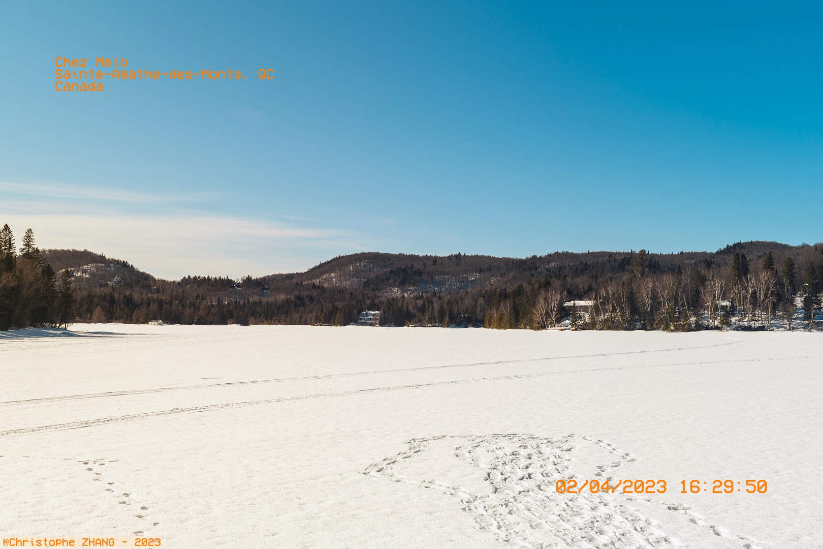Paysage hivernal d’un lac gelé entouré de collines boisées à Sainte-Agathe-des-Monts.
