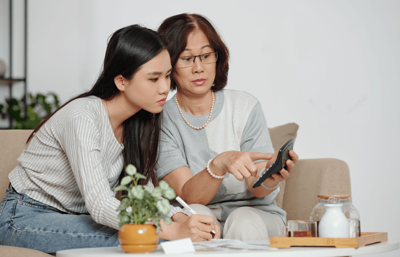 senior woman and younger looking at calculator