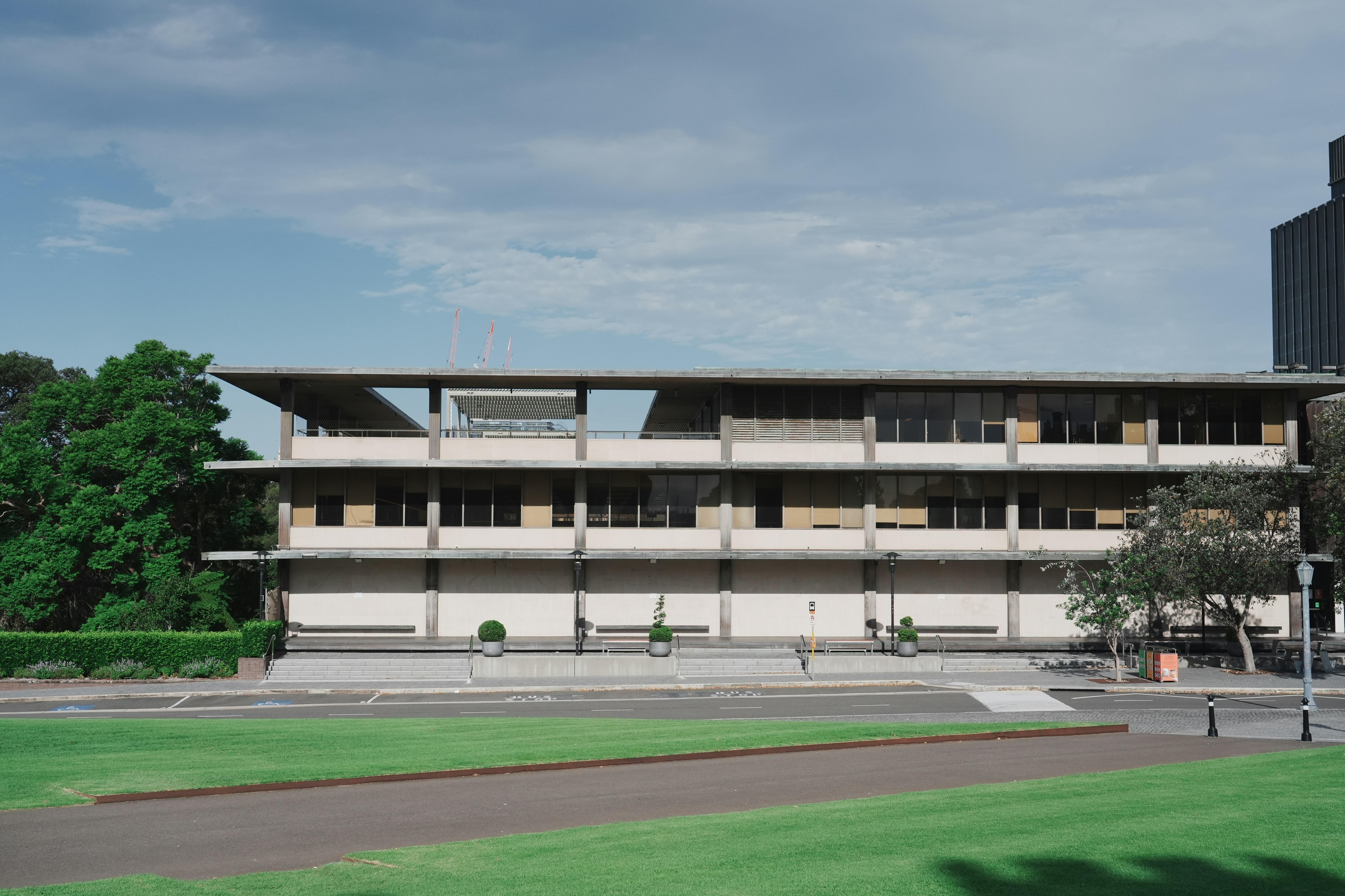 Modern concrete building with balconies and trees.