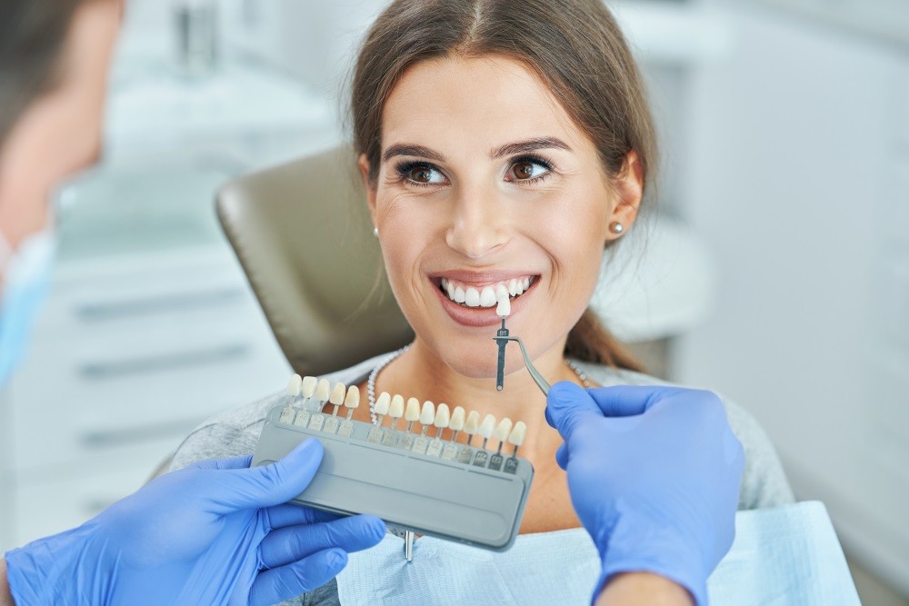 Woman choosing tooth shade for dental crowns