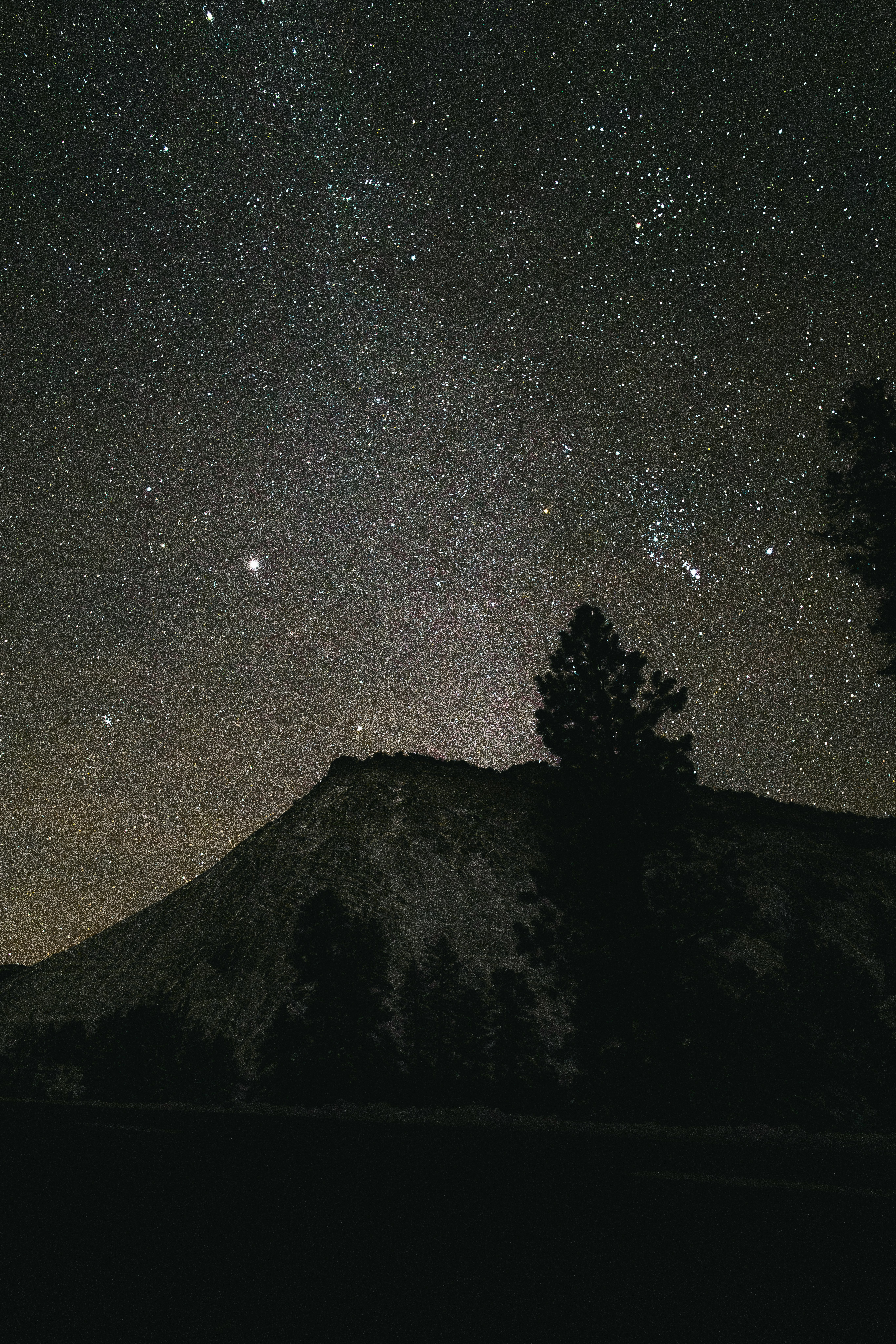 Starry night sky over a silhouetted mountain peak.