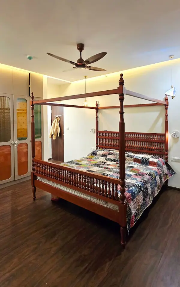 Luxury wooden four‑poster bed with turned pillars and patterned quilted bedding