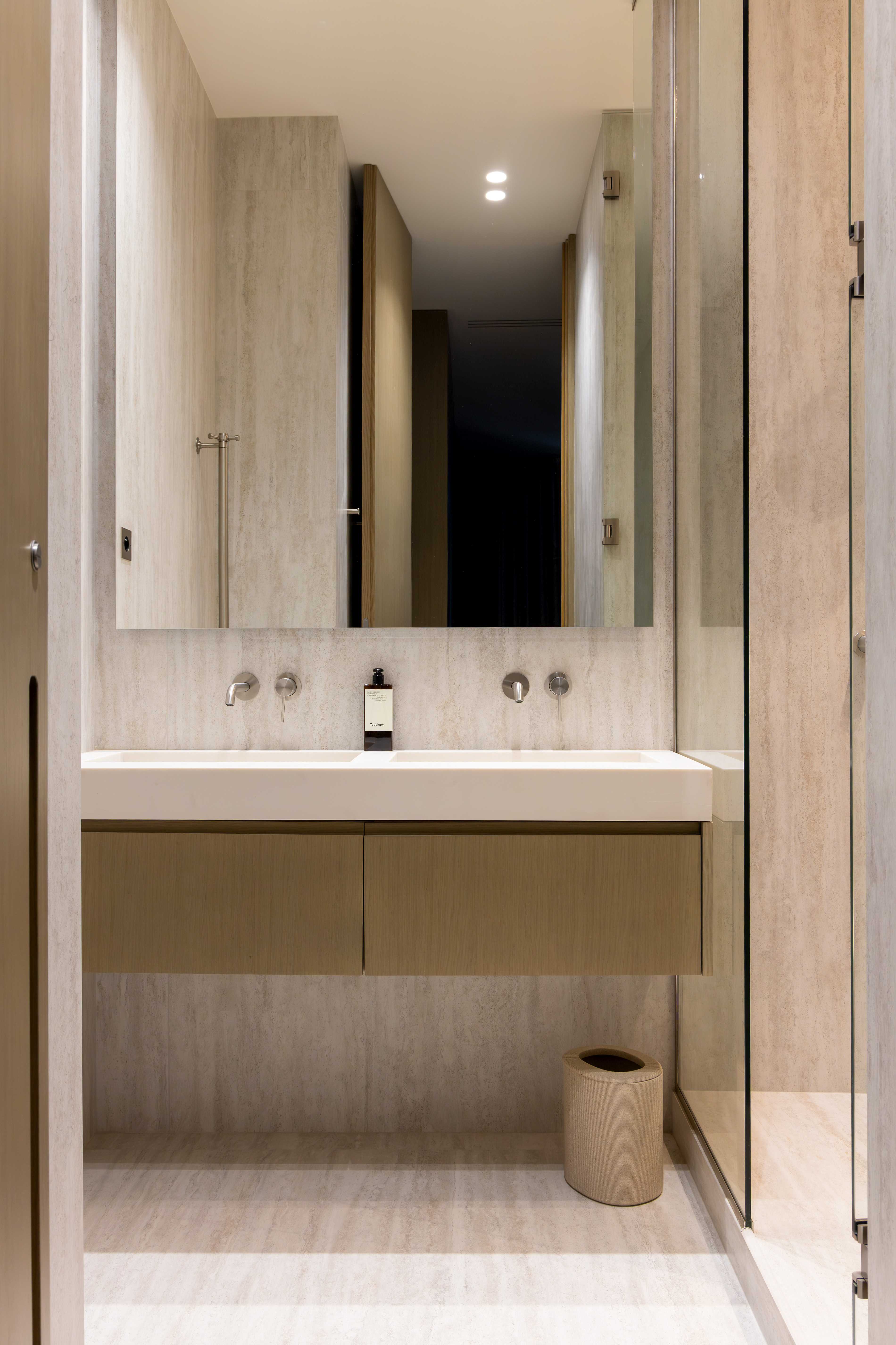 Salle de bain avec vasque suspendue en bois clair, grand miroir et robinetterie murale nickel