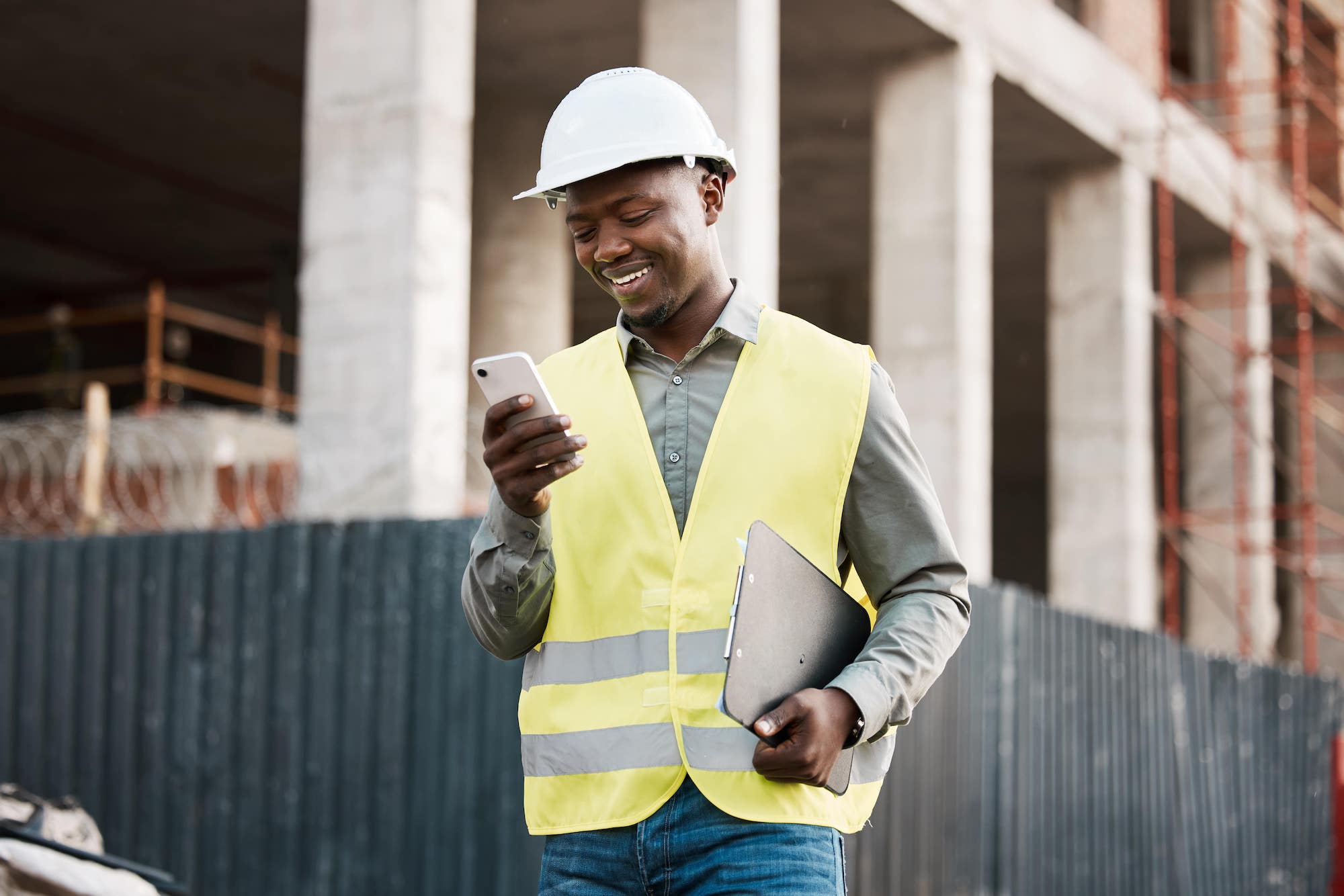 Photo of smiling construction worker looking at his mobile phone