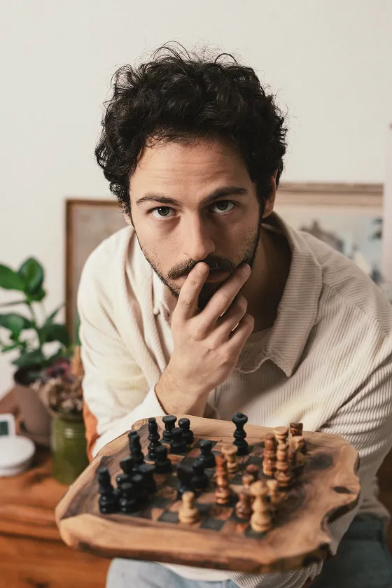 SukOne mit nachdenklicher Pose und einem Schachbrett in der Hand
