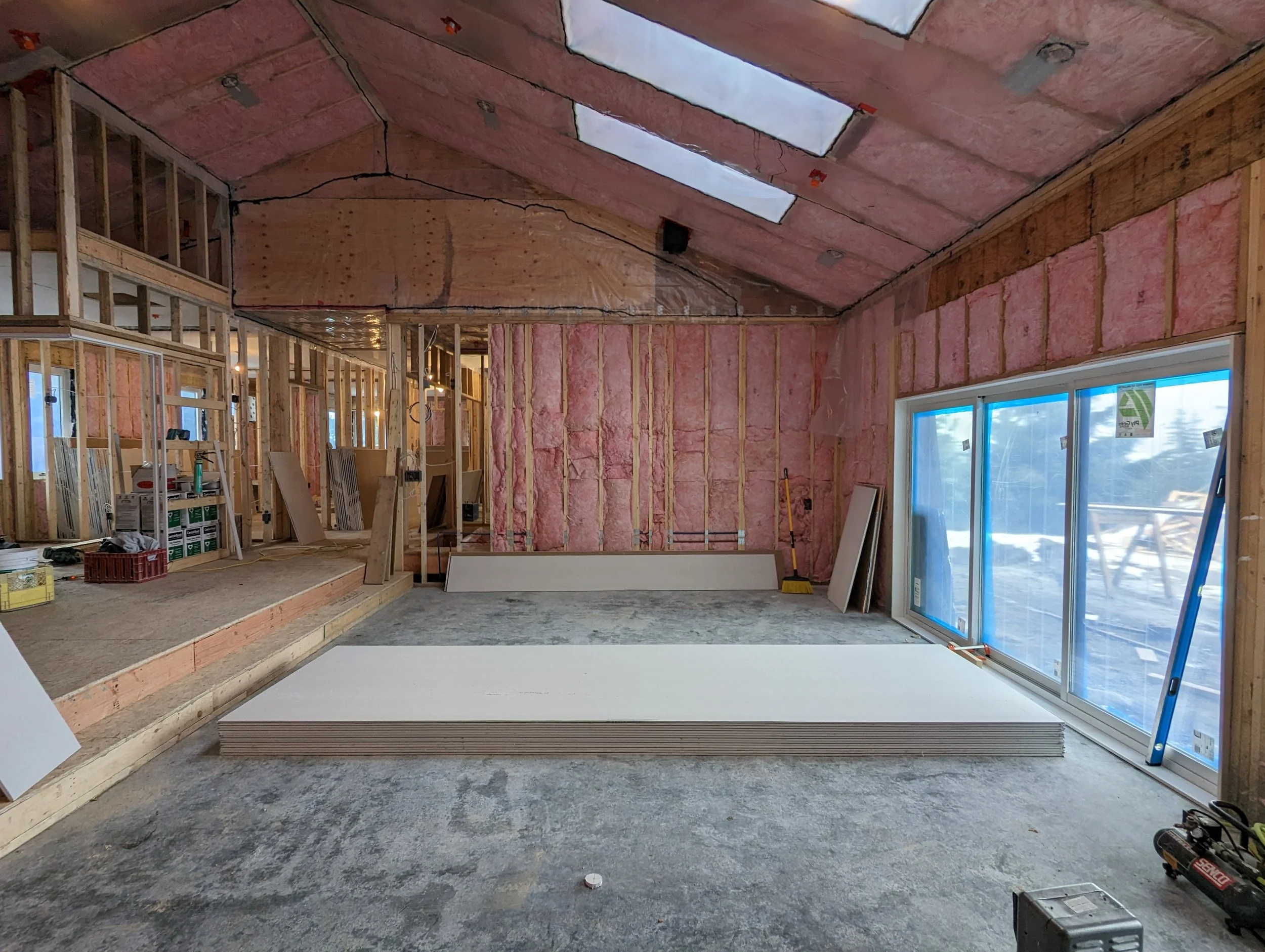 Modern two-story home with large glass windows, warmly lit interiors, and a balcony. Surrounded by trees and a manicured lawn at dusk. Cozy ambiance.