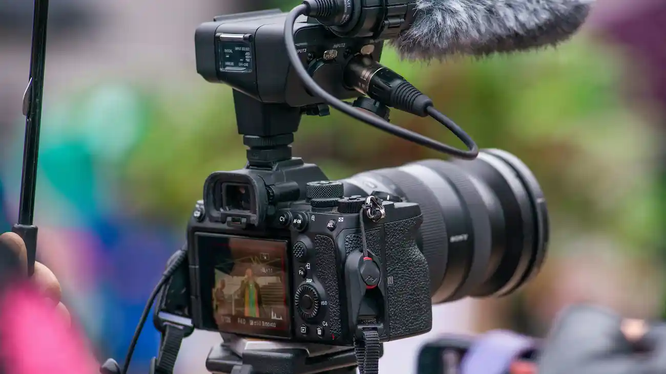 Professional video camera with microphone filming an outdoor event, representing PR, media relations, photo calls and press coverage for sports club sponsorship.