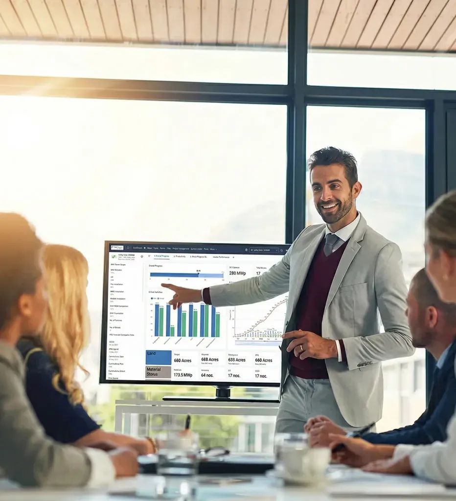 A man presents data on a screen to a group of colleagues in a modern office setting.