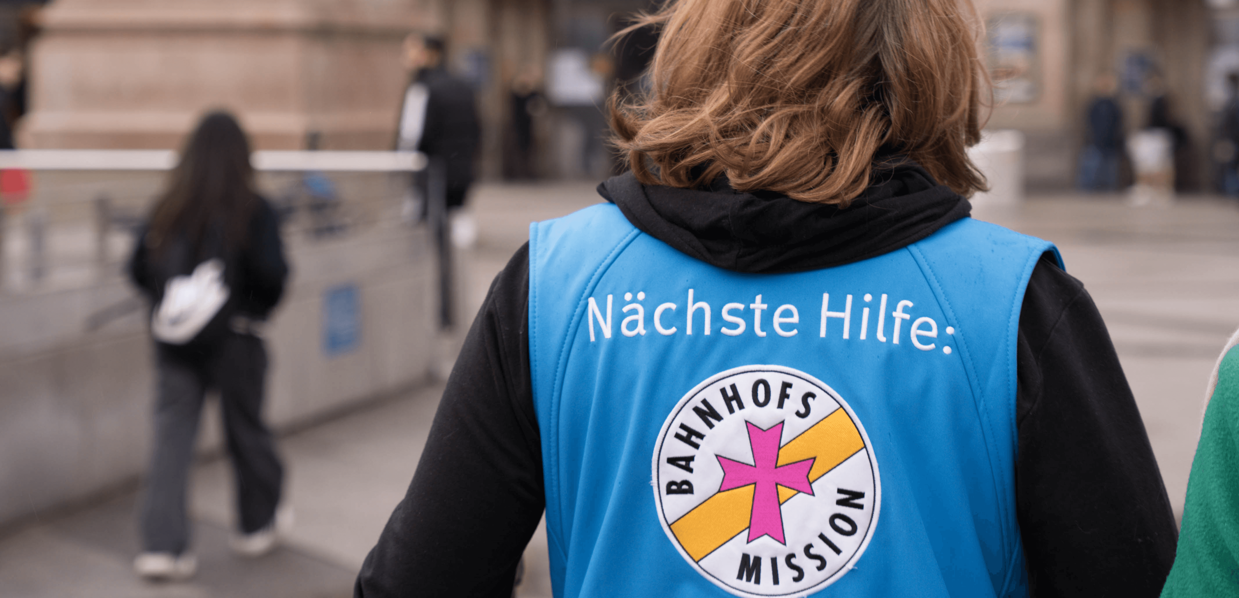Mitarbeiterin der Bahnhofsmission Hannover hilft hilfesuchender Person am Hauptbahnhof