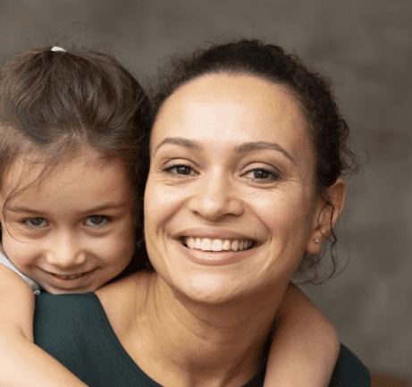 Smiling Mom with her daughter on her back.