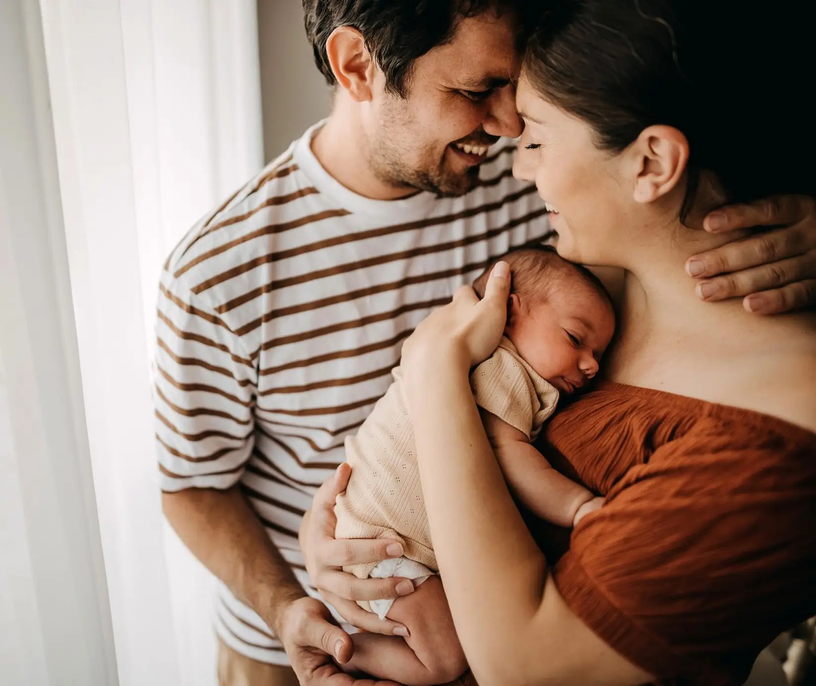 Parents holding newborn baby during postpartum bonding at home