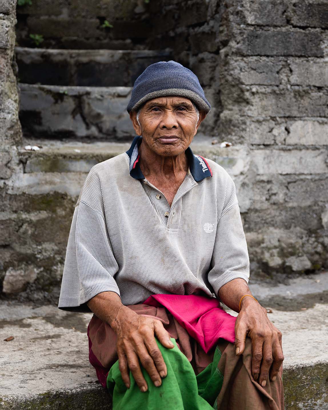 Portrait of an Indonesian man sitting on an old brick staircase.