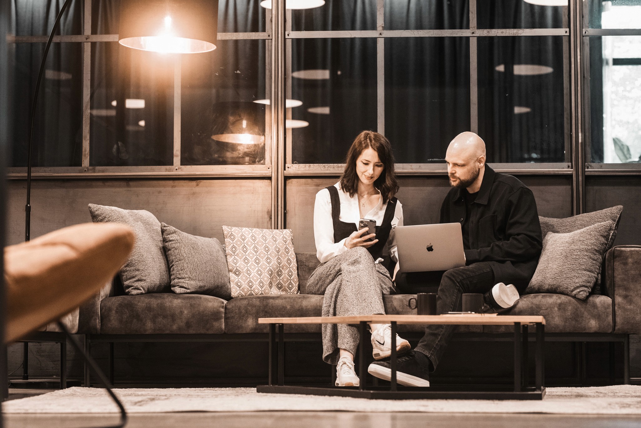 Three people sitting on a couch in a room looking at mobile devices