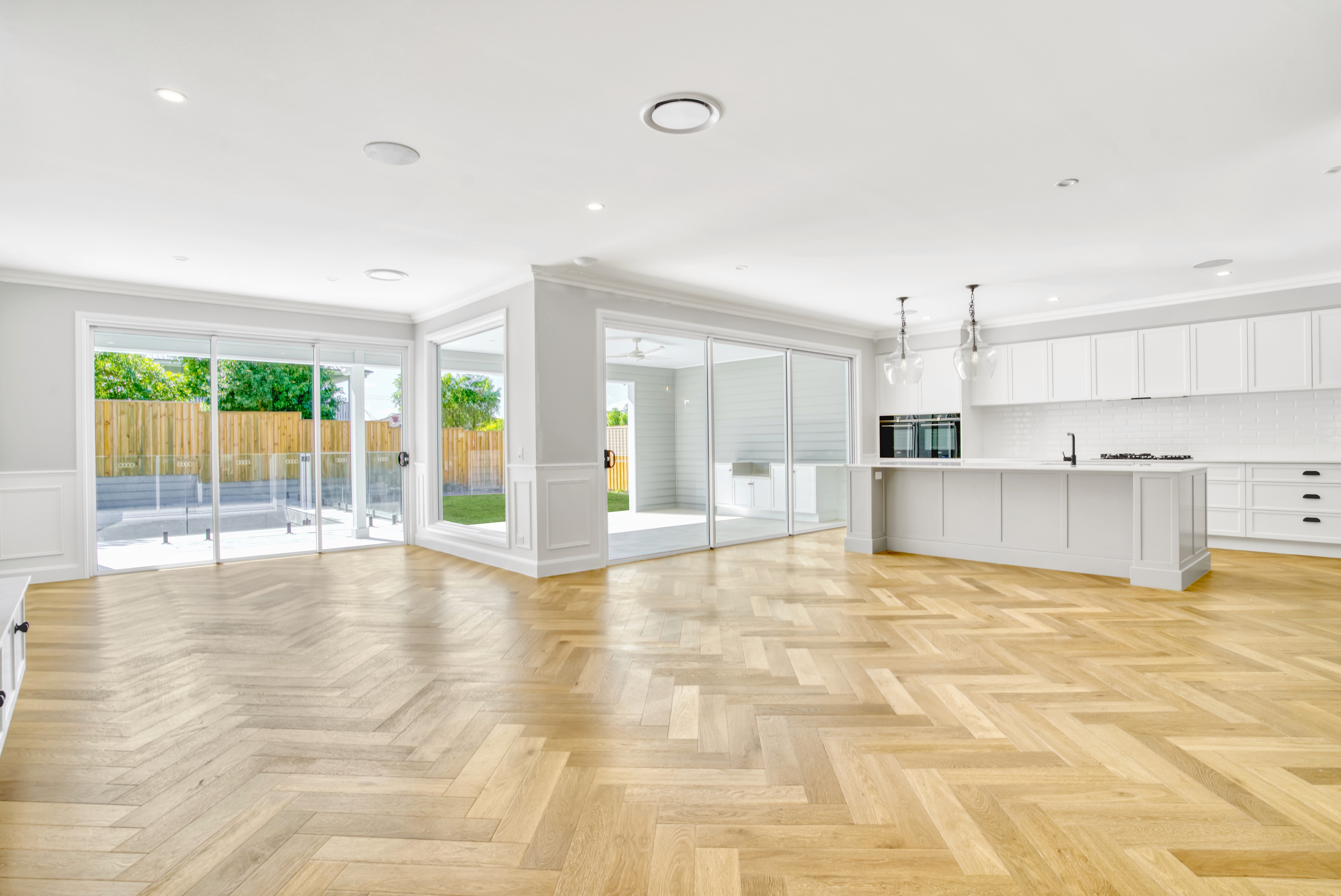 Open-plan kitchen and living area flowing into an alfresco space in a custom Brisbane home.