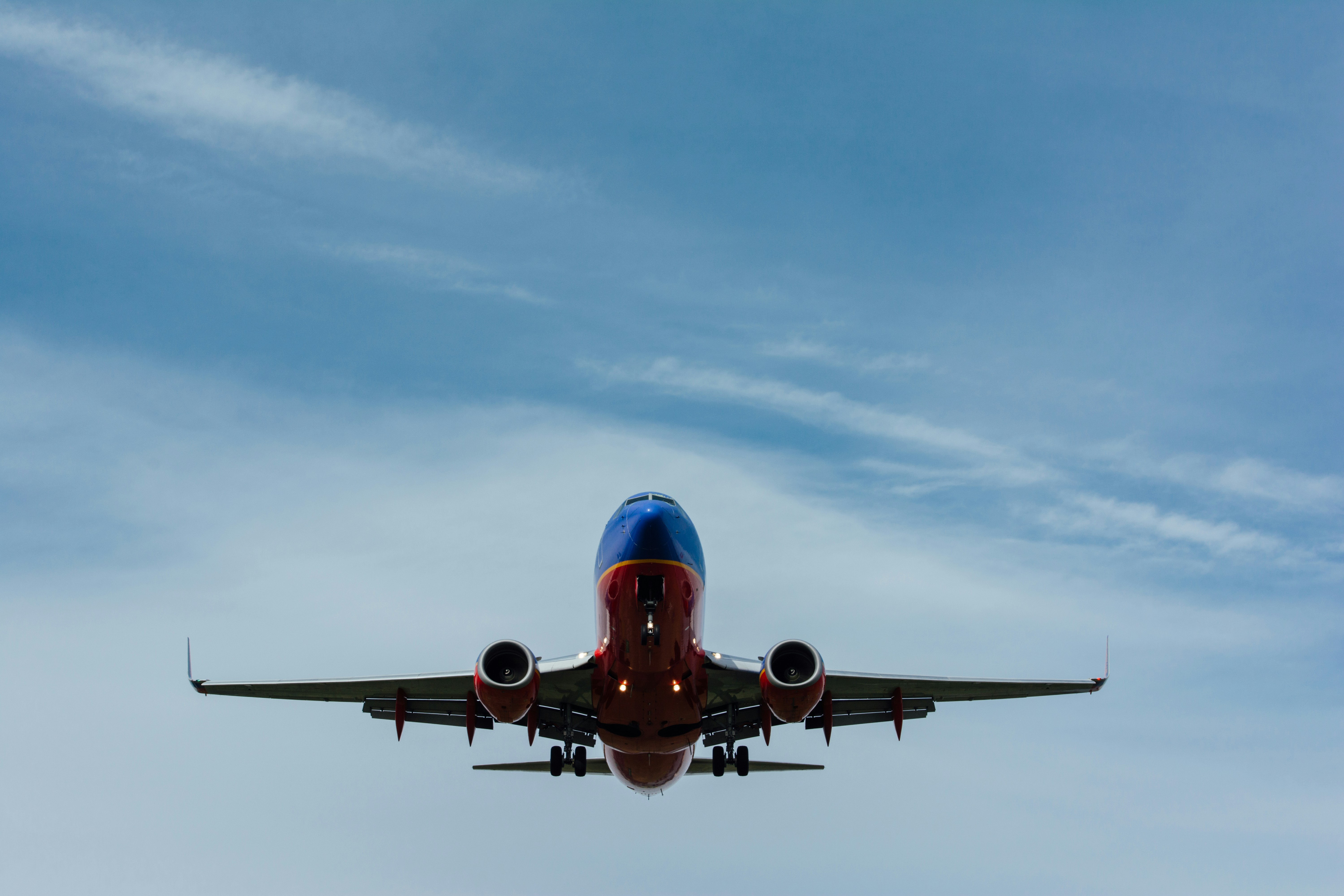 A red and blue airplane flying in a blue sky