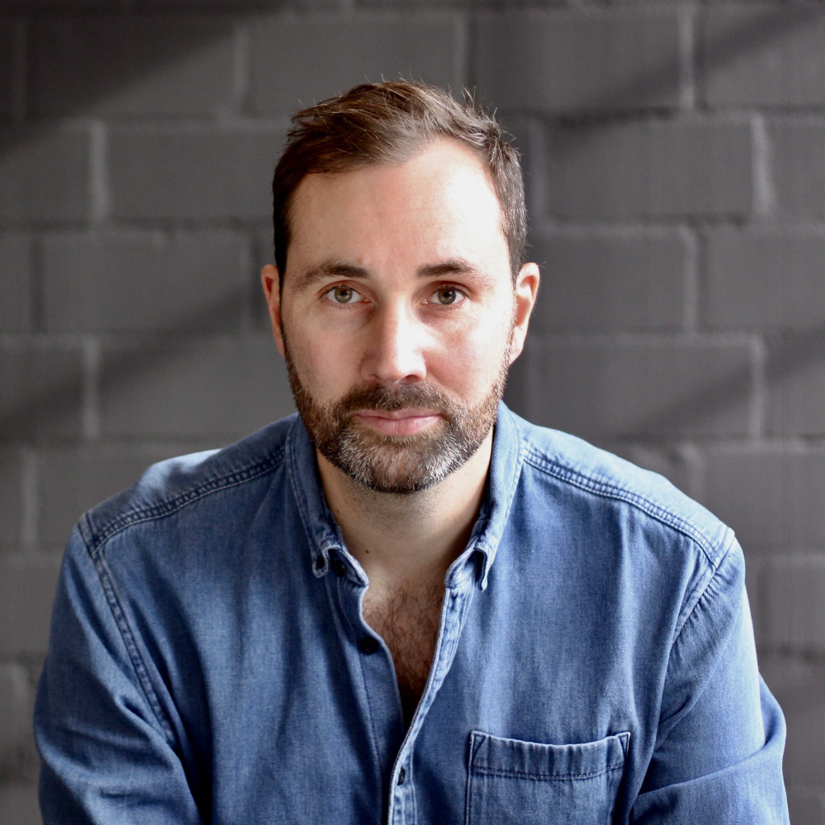 Smiling woman in a dark blazer against a blue sky