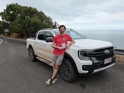 Jamie Patrick standing in front of a truck in front of the ocean