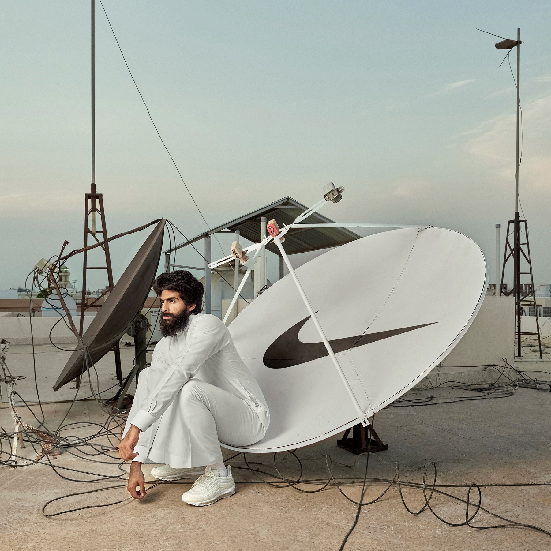 Man seated beside a Nike-branded satellite, photographed by Nawawi Studio, reimagining 90s nostalgia through the Nike x Vice collaboration.