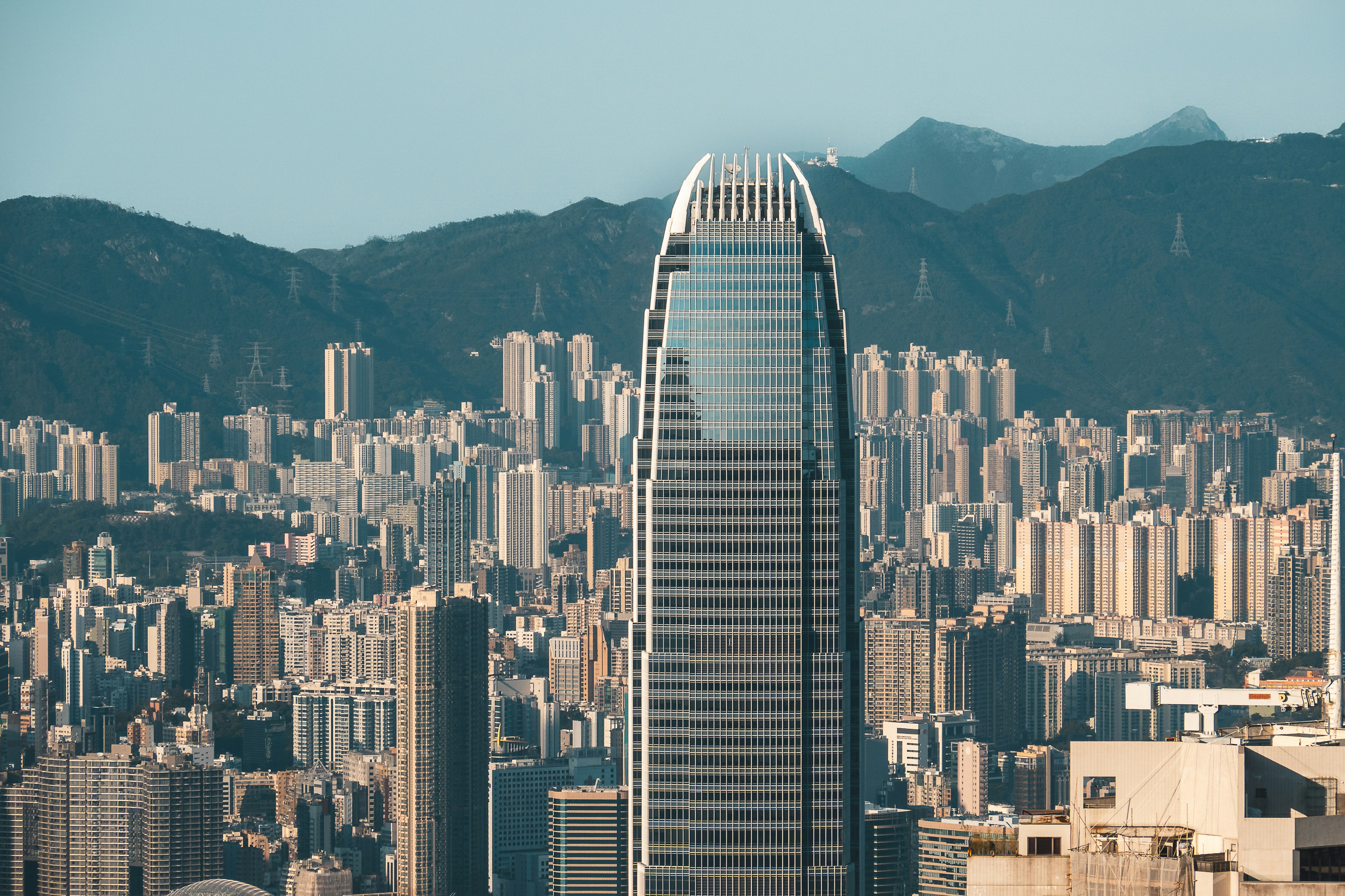 Modern skyscraper in a dense cityscape with mountains behind