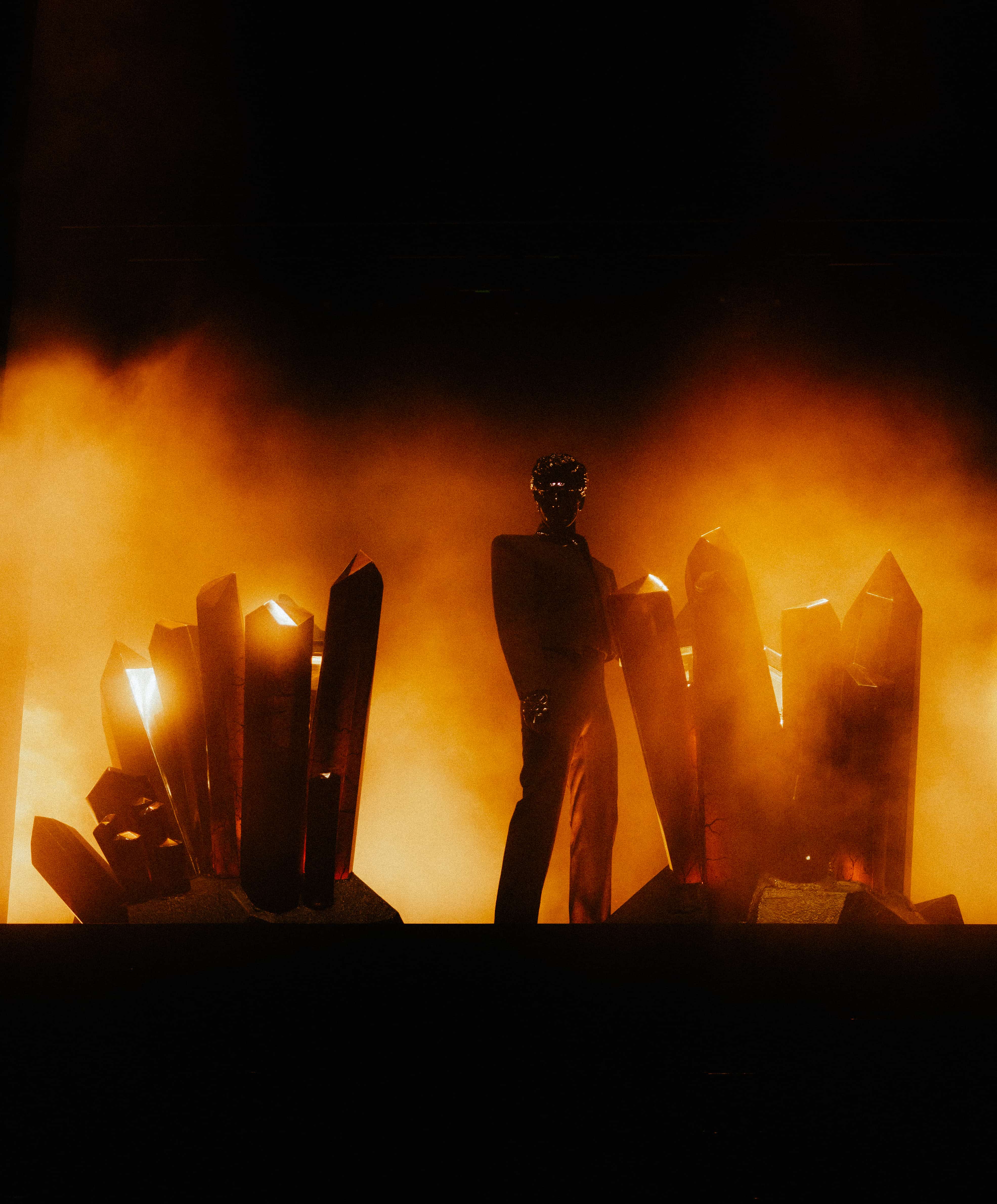 Gesaffelstein performing at Coachella 2024 in silhouette surrounded by illuminated crystal stage elements and orange haze, captured by A World Away creative director Brandon Densley