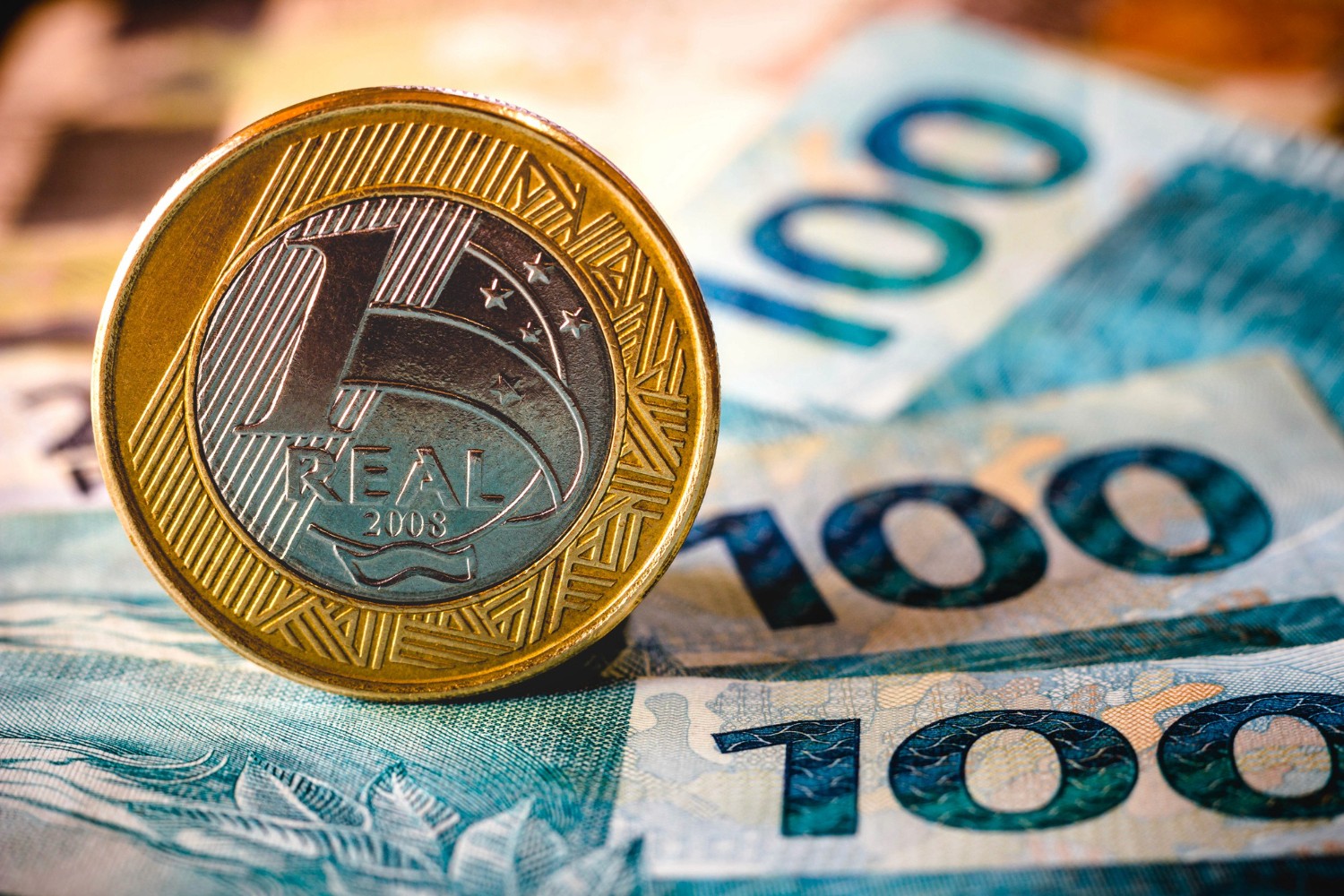 moeda de 1 real e nota de 100 reais