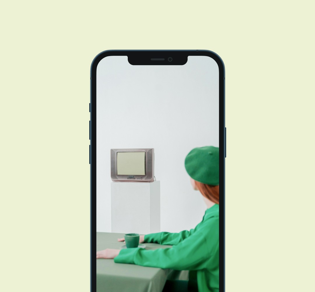 A mockup of a phone displaying an image of a woman looking at a television